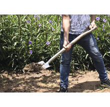 Personne avec une bêche dans le jardin retournant la terre