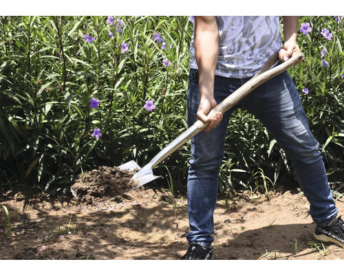 Personne avec une bêche dans le jardin retournant la terre