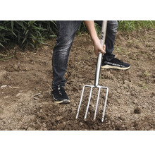 Person verwendet eine Mistgabel im Garten.