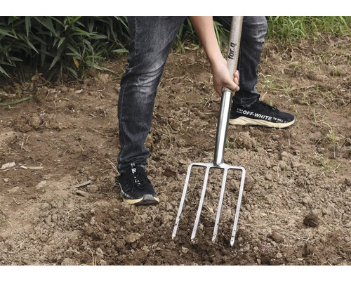 Person verwendet eine Mistgabel im Garten.