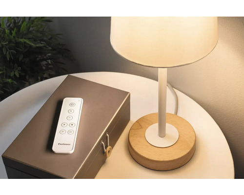 Lampe mit Holzfuß, Fernbedienung und einer dekorativen Box auf einem Tisch