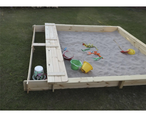 Sandkasten aus Holz mit Spielzeug im Garten