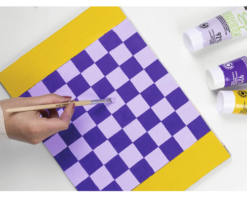 Une personne peint un motif en damier avec un pinceau et de la peinture.