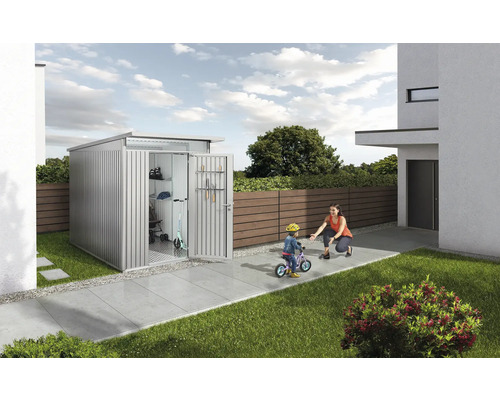 Abri de jardin métallique avec porte ouverte dans le jardin, une mère aide son enfant à faire du vélo