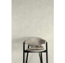 Stuhl mit Textilbezug, Büchern und Schale vor einer Wand