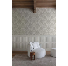 Wohnraum mit gemusterter Tapete, gepolstertem Sessel und Holzschemel