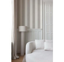 Innenaufnahme eines Raumes mit gestreifter Tapete, Stehlampe und Sofa.