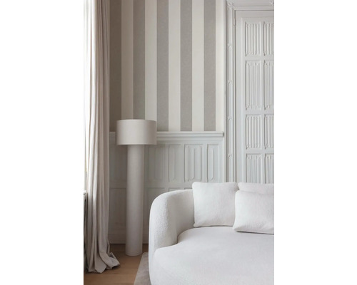 Innenaufnahme eines Raumes mit gestreifter Tapete, Stehlampe und Sofa.