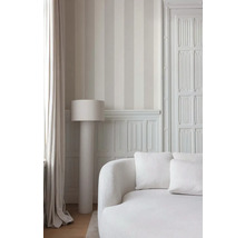 Heller Raum mit gestreifter Tapete, Stehlampe und Sofa.