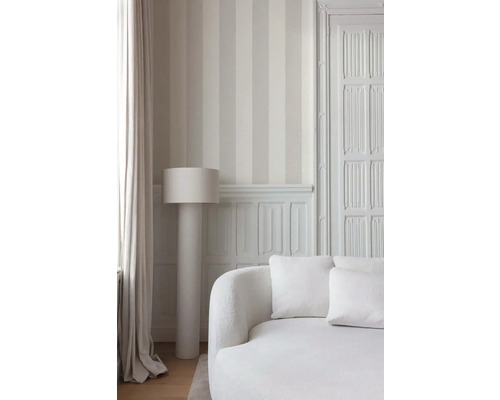Heller Raum mit gestreifter Tapete, Stehlampe und Sofa.