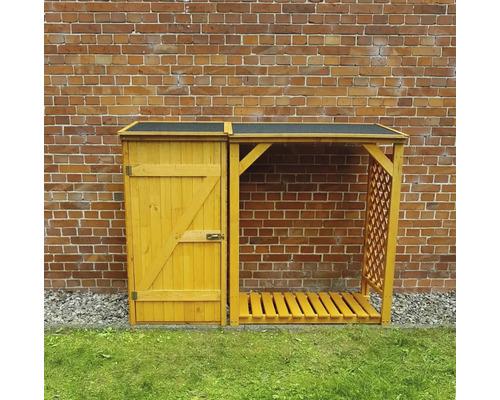 Hangar à bois avec porte et treillis devant un mur de briques