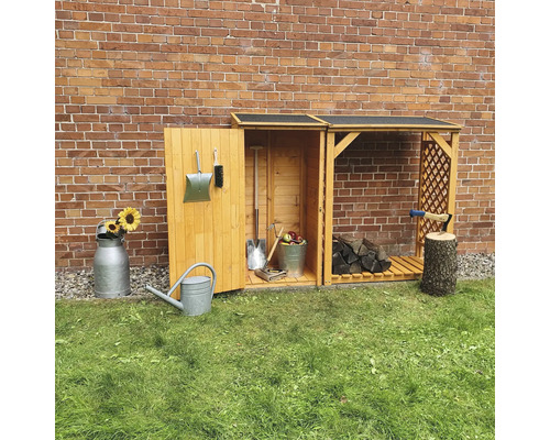 Abri à outils en bois avec outils de jardin et bois de chauffage devant un mur de briques