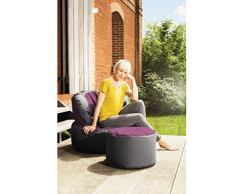 Frau sitzt im Garten auf einem Sitzsack mit Hocker