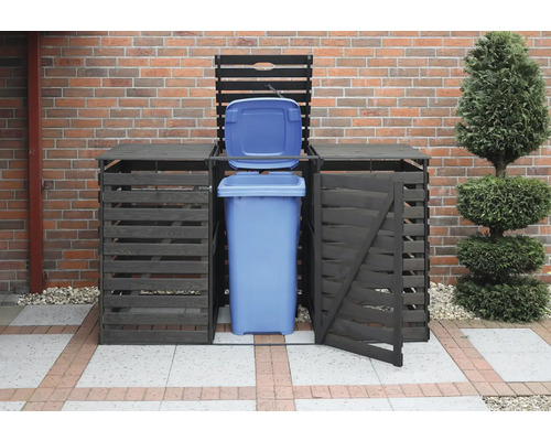 Cache-conteneur avec poubelle bleue ouverte devant un mur en briques