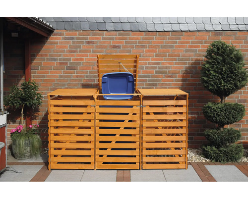 Trois caches poubelles en bois devant un mur en briques