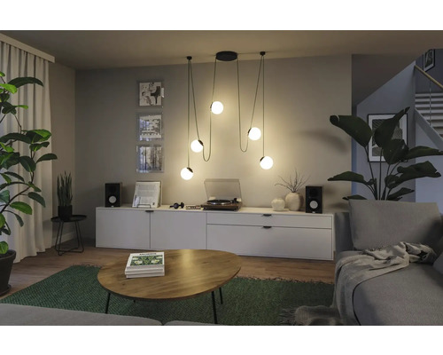 Salon avec suspension, commode, tourne-disque et plantes d''intérieur pour une ambiance chaleureuse.