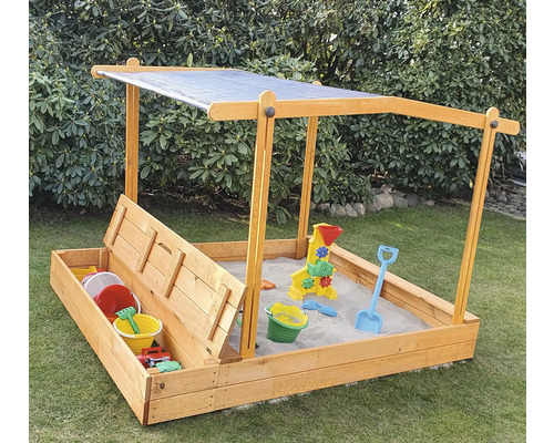 Bac à sable avec protection solaire et jouets dans le jardin