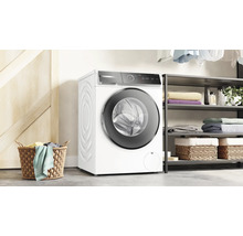 Machine à laver blanche à côté d''une étagère avec du linge et un panier à linge