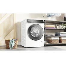 Machine à laver à chargement frontal dans une pièce lumineuse avec un panier à linge et une étagère.