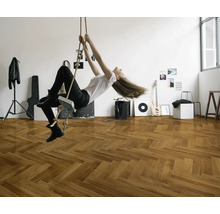 Une femme se balance à une corde dans une pièce avec un parquet en point de Hongrie.