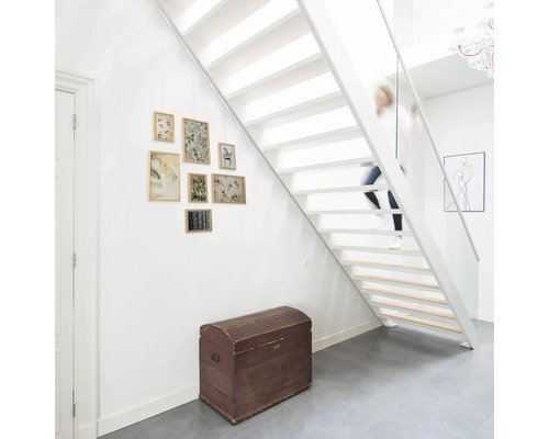 Weißes Treppenhaus mit Holztreppe, Truhe und Bilderrahmen