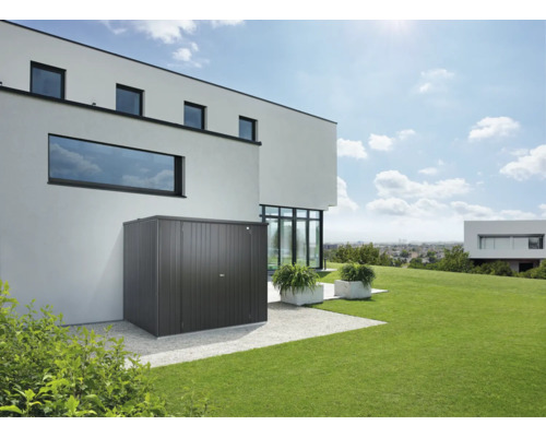 Gartenhaus aus Metall neben einem modernen Wohnhaus mit Rasenfläche