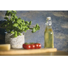 Stillleben mit Basilikumpflanze in einem Topf, Tomaten und einer Flasche Öl auf einem Holztisch.