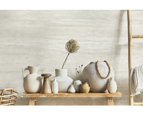 Vases décoratives en céramique sur une table en bois rustique, complétées par une échelle en bambou avec des textiles et un mur à motif horizontal.