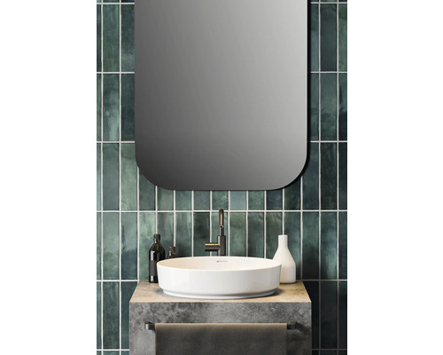 Meuble de salle de bain avec lavabo à poser, robinet et miroir devant un carrelage vert