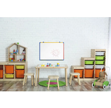 Kinderzimmer mit Spielzeugregalen, Tisch, Stühlen und einer Maltafel an einer weißen Ziegelwand