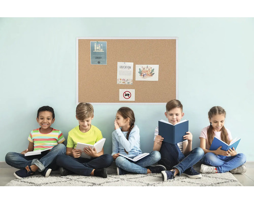 Cinq enfants sont assis devant un panneau de liège et lisent des livres.