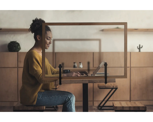 Femme travaillant sur un ordinateur portable avec un panneau de protection sur la table