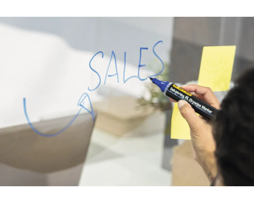 Une personne écrit le mot ventes sur une surface transparente avec un stylo effaçable à sec.