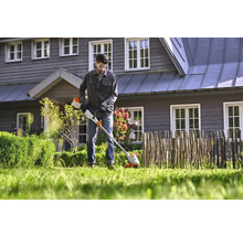 Un homme utilise un coupe-bordure sans fil dans le jardin.