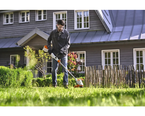 Un homme utilise un coupe-bordure sans fil dans le jardin.