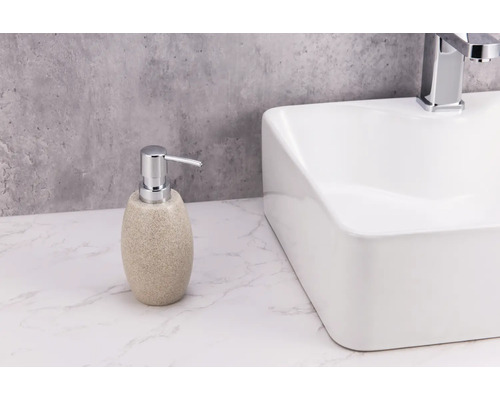 Seifenspender aus Stein neben einem weißen Waschbecken.