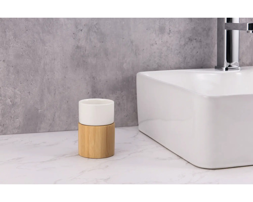 Gobelet à brosses à dents en céramique et bambou à côté d''un lavabo