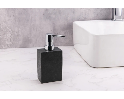 Distributeur de savon en pierre avec pompe chromée à côté du lavabo