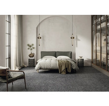 Schlafzimmer mit Bett, Nachttischen, Stehleuchten und einem Sessel auf einem Terrazzoboden.