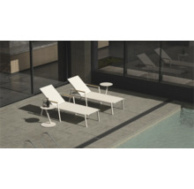 Deux chaises longues blanches et tables d'appoint au bord de la piscine