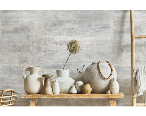 Dekorative Vasen und eine Leiter aus Bambus auf einem Holztisch vor einer Wand mit Putzstruktur.