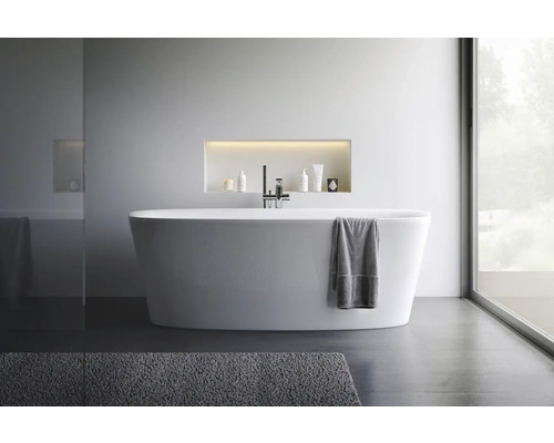 Modernes Badezimmer mit freistehender Badewanne, Armatur und Pflegeprodukten in einer Nische.