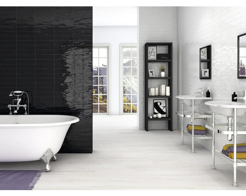 Salle de bains avec baignoire îlot, carreaux muraux noirs et blancs, étagère et lavabos