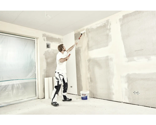 Mann streicht Wand mit Farbroller in einem Raum, Renovierungsprojekt