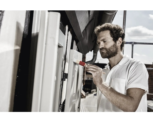 Un homme peint une structure en bois à l''extérieur avec un pinceau