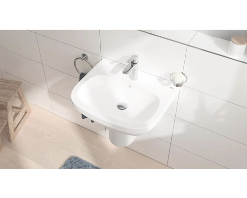 Salle de bains compacte avec lavabo suspendu, robinet, porte-serviettes et porte-savon.