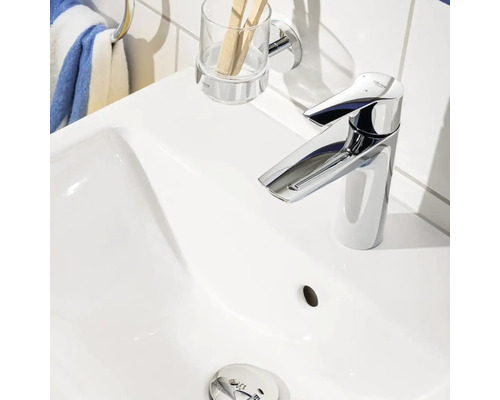 Photo d''un lavabo blanc avec un robinet brillant, un gobelet à brosses à dents et un porte-serviettes