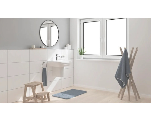 Salle de bain lumineuse avec lavabo, miroir, porte-serviettes et tapis de bain