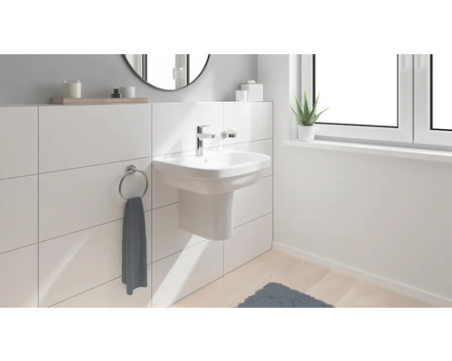Salle de bain lumineuse avec lavabo à poser, anneau porte-serviette et fenêtre pour une ambiance moderne.
