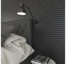 Schlafzimmer mit Bett, Lampe und Wandpaneelen